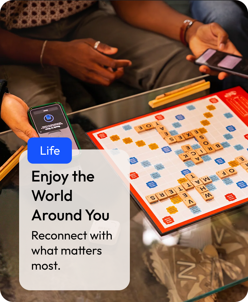 Text reads: 'Life: Enjoy the world around you. Reconnect with what matters most.' People playing Scrabble with a smartphone in the foreground and a motivational message overlay.